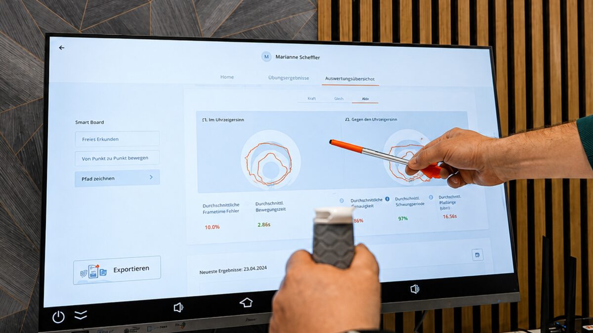 A therapist pointing at a Smart Board results report showing movement traces and accuracy metrics.
